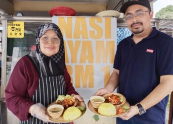 SUHAIMI Sulaiman (kanan) bersama Rokhiah Abd. Hamid menunjukkan nasi ayam RM1 yang dijual di gerai makan Pak Uda Corner, Batu Berendam, Melaka. - UTUSAN/MUHAMMAD SHAHIZAM TAZALI