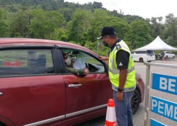 BAHARUDIN Abdullah memeriksa sebuah kereta yang melalui sekatan jalan raya (SJR) Paka di Dungun hari ini. - NIK NUR IZZATUL HAZWANI NIK ADNAN