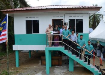 DR. Abdul Aziz Sheikh Abdul Kadir (kiri) menyerahkan replika kunci rumah kepada Rahimah (tiga dari kiri) pada Majlis Penyerahan Rumah Mawaddah di Kampung Jimah Lama, Port Dickson hari ini.-UTUSAN/ZAKKINA WATI AHMAD TARMIZI.