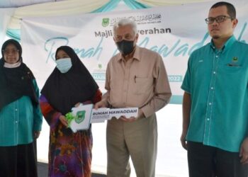 DR. ABDUL Aziz Sheikh Abdul Kadir (dua dari kanan) menyerahkan replika kunci rumah kepada Rahimah Abdul Majid pada Majlis Penyerahan Rumah Mawaddah di Kampung Jimah Lama, Port Dickson hari ini.-UTUSAN/ZAKKINA WATI AHMAD TARMIZI.