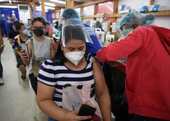 PETUGAS kesihatan memberi suntikan vaksin Covid-19 kepada
penduduk di sebuah pusat vaksinasi sementara di bandar
Mandaluyong, Manila. – AFP