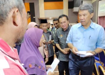 MOHAMAD Hasan (kanan)  dan Mohd. Salim (dua dari kanan) menyampaikan dividen TSK kepada peserta pekebun kecil pada Majlis Pekebun Kecil Makmur dan Penyampaian Dividen TSK  Risda Peringkat Negeri Sembilan 2022 di Dewan Biduanda, UiTM Rembau, Rembau hari ini.-UTUSAN/ NOR AINNA HAMZAH.