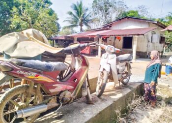 RAHA Musa melihat motosikal milik anaknya yang rosak selepas ditenggelami air banjir di Kampung Serongga Pasir Mas, Kelantan. - UTUSAN/ROHANA ISMAIL