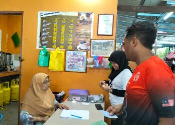 SINAH Sulaiman (kiri) melayan pelanggan yang membayar harga makanan dan minuman di warungnya 
di Losong, Kuala Terengganu. – UTUSAN/KAMALIZA KAMARUDDIN