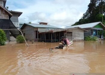 PENDUDUK terpaksa menggunakan perahu untuk melakukan aktiviti harian berikutan banjir yang berlaku di Sembakung. - AGENSI