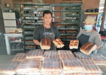 FARAH Nadia Abdul Ghafoor (kanan) menunjukkan roti yang dibakar menggunakan kayu yang telah siap diproses di Lorong Masjid, Kampung Bahagia di Teluk Intan. - UTUSAN/AIN SAFRE BIDIN