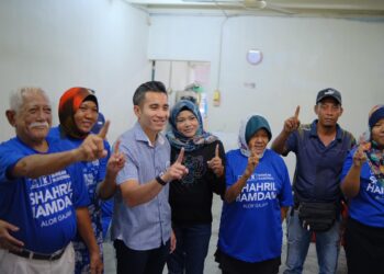 SHAHRIL Sufian Hamdan (tiga dari kiri) menunjukkan simbol satu mewakili nombor calonnya bersama para pengundi di Parlimen Alor Gajah, Melaka.