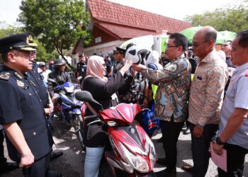 SULAIMAN Md. Ali memakaikan topi keledar kepada seorang penunggang motosikal selepas melancarkan MKJR Melaka sempena Kempen Keselamatan Jalan Raya dan Op Tahun Baru Cina di Ayer Keroh, Melaka. - UTUSAN/AMRAN MULUP