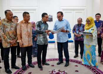 ANWAR Ibrahim (kanan) bersama Onn Ghazi meneliti buku Maju Johor dalam pertemuan semalam.