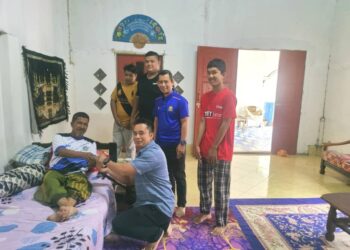 KAMARUL Azman Khamis (dua dari kiri) menyampaikan sumbangan ketika bersama mahasiswa UUM menziarahi seorang penduduk 
di Kampung Baru Tualak, Padang Terap hari ini.-UTUSAN