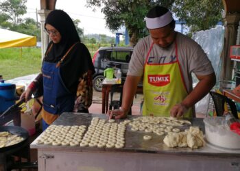 IDHAM Shafiq Darmilus dan Edah Ali tekun menghasilkan donut bersaiz mini untuk dijual di Kampung Baru Kuala Abang, Dungun. – UTUSAN/NIK NUR IZZATUL HAZWANI NIK ADNAN