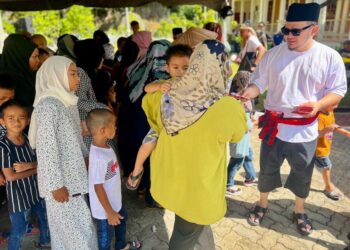 FATHUL Bari Mat Jahya (kanan) memberi duit raya kepada kanak-kanak sewaktu Majlis Rumah Terbuka UMNO Bahagian Kangar di Muzium Kota Kayang, Kangar, Perlis, semalam. -UTUSAN/ASYRAF MUHAMMAD