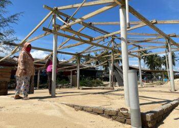 AMINAH Jusoh bersama bangsal memproses ikan kering yang tinggal kerangka di Kampung Pantai Pachakan, Pasir Puteh semalam. - UTUSAN/TOREK SULONG