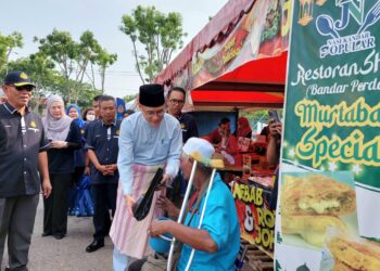 ZAIRIL Khir Johari (kanan) bersama Adenan Md. Isa (tengah) ketika mengagihkan bungkusan kuih raya dan risalah keselamatan jalan raya kepada orang ramai di bazar Ramadan Taman Pauh Indah, Bukit Mertajam, Pulau Pinang hari ini.