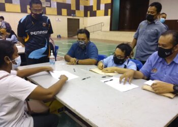 MOHD. Faizal Abdul Raji (duduk, dua dari kiri) dan Mohd. Fakhrulrazi (berdiri, kiri) meninjau penyerahan sumbangan mangsa banjir di Dewan MPK Meru di Klang, Selangor.