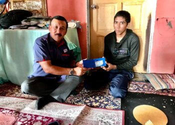 RUSLIN Jusoh (kiri) menyerahkan MyKad kepada Mohammad Haffiq di Kampung Padang Enggang, Kota Bharu, Kelantan semalam.UTUSAN/ROSLIZA MOHAMED