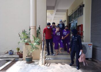 Kok Chaw Fatt (dua dari kiri) menutup mukanya ketika dibawa keluar dari Mahkamah Sesyen Raub di Raub, Pahang. - UTUSAN/AZIZAH SHAFIEI