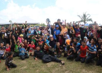 ISMAIL Abdul Muttalib (tengah, baju warna biru) bersama penduduk di program mengemping padi Paya Bukit Chempedak di Maran hari ini. - UTUSAN/SALEHUDIN MAT RASAD