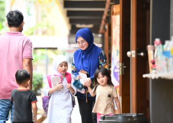 SITI Nurazlina Jamaludin menemani anaknya pulang dari sekolah setelah selesai menerima agihan Bantuan Awal Persekolahan di Sekolah Kebangsaan (SK) Seri Indera, Kangar, Perlis.- hari ini. - UTUSAN/IZLIZAN OTHMAN