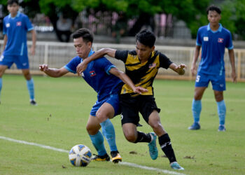 PEMAIN sayap Malaysia, Muhammad Zulkarnain Mohd. Nasir mengasak pemain Laos, Souksavanh Xayalin pada aksi di Stadium Universiti Ubon Ratchathani Rajabhat hari ini.