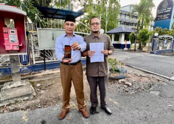 MOHD. Shukri Ramli (kiri) menunjukkan poster pelaburan yang menyalahgunakan gambarnya selepas membuat laporan di Ibu Pejabat Polis Daerah (IPD) Kangar, Perlis hari ini. -UTUSAN/ASYRAF MUHAMMAD