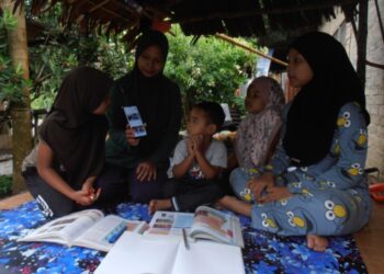 NOOR Janatul Abd. Razak (dua kiri) menggunakan telefon pintar miliknya semasa sesi PdPR tiga anaknya, Nur Auni Safiah (kanan), Nur Afrina Amani (kiri) dan Nur Nadwatul Hawa (dua kanan) di rumah ibunya di Kampung Baru, Pendang, Kedah, semalam. –UTUSAN/OTHMAN YAHAYA
