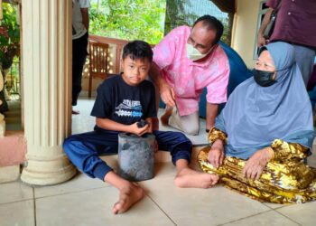 MUHAMMAD Amzar Haziq Mohd. Azlan menunjukkan wang yang disimpan dalam tin biskut yang musnah dalam kebakaran  rumahnya di Felda Lubok Merbau di sini semalam. - UTUSAN/MOHD. RIFAAT ABD. HAMID