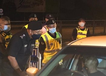 SHAFIEN Mamat bertanyakan sesuatu kepada pemandu ketika menyertai operasi sekatan jalan raya pada hari pertama PKP di Tumpat, semalam.