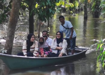 MARIE Suriani Abdullah bersama keluarganya menaiki bot untuk keluar mengundi selepas jalan masuk ke rumahnya Kampung Tersang, Rantau Panjang, Kelantan masih ditenggelami air hari ini. - UTUSAN/ROSALWANI CHE SOH