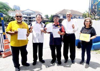 ABDUL RAZAK Dawood (kiri) menunjukkan laporan polis mengenai isu Datuk palsu itu di Balai Polis Puchong Jaya di Puchong, Selangor semalam.