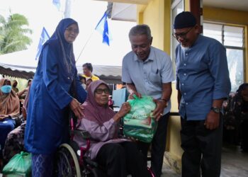 OTHMAN Aziz (dua kanan) bersama-sama Ahmad Nazlan Idris (kanan) menyampaikan sumbangan bakul makanan kepada salah seorang penerima, Habsah Awang, 78, pada Program CSR PUNB di Kuala Kerpan, Jerlun hari ini. -UTUSAN/ SHAHIR NOORDIN