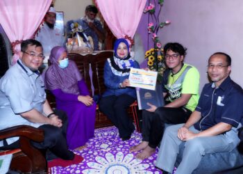NORAINI Ahmad (tengah) menyerahkan surat tawaran Program Pembangunan Siswa Sulung Keluarga Malaysia kepada Muhammad Hakimi Yunus (dua dari kanan) di Taman Seri Bayan, Gangsa, Durian Tunggal, Melaka. - UTUSAN/RASUL AZLI SAMAD