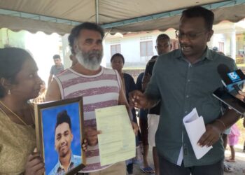 Dayalan Sreebalan (kanan) bersama kedua ibu bapa menunjukkan gambar C. Lakshman yang sudah siap dibingkaikan untuk proses pembakaran mayat ketika ditemui di Taman Desa Permai Repah, Tampin semalam.-UTUSAN/NOR AINNA HAMZAH