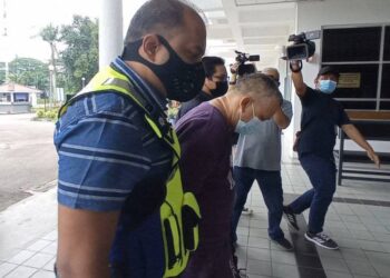 Mohd Zahazan (depan) dibawa ke Mahkamah Majistret Kota Tinggi atas pertuduhan memperdaya rakan sekerja untuk mendapatkan derma semalam.
