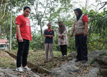 KERK Chee Yee (kiri) meninjau lokasi pembuangan sisa simen ke dalam longkang di Taman Bukit Katil Damai, Melaka. - UTUSAN/SYAFEEQ AHMAD