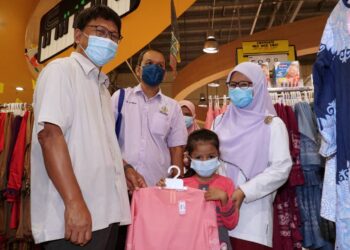ASMUNI Awi (kiri) bersama penerima sumbangan membeli baju raya di Meru Raya, Ipoh hari ini.  - UTUSAN/ZULFACHRI ZULKIFLI