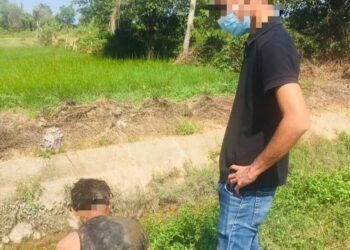SEORANG lelaki yang terjun ke parit berlumuran lumpur ketika ditahan pasukan AADK di Pasir Puteh, Kelantan, semalam. - IHSAN AADK