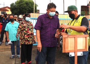PETUGAS SPR membantu pengundi yang hadir pada hari mengundi Pilihan Raya Negeri (PRN) Melaka di Sekolah Kebangsaan Durian Tunggal, Alor Gajah. - UTUSAN/RASUL AZLI SAMAD