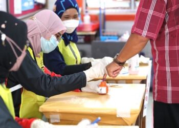 PENGUNDI dikenakan dakwat sebelum mengundi Pilihan Raya Negeri (PRN) Melaka di Sekolah Kebangsaan Durian Tunggal, Alor Gajah. - UTUSAN/RASUL AZLI SAMAD