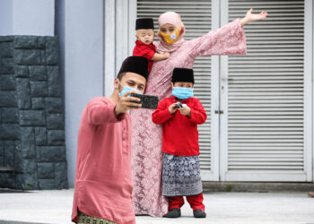 WAN Hami Wan Isa, 33, mengambil kesempatan merakam gambar kenangan bersama keluarganya di Taman Tasik Shah Alam, Selangor hari ini. - UTUSAN/AFIQ RAZALI