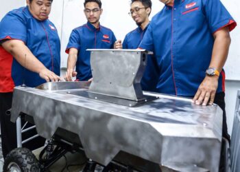 Shaifull (kanan) bersama pasukan inovasinya meneliti robotik yang terbaharu dibangunkan, Unmanned Ground Vehicle bagi kerja-kerja pemantauan.