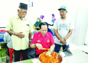 AHMAD Maslan membungkus otak-otak semasa melawat sebuah kilang 
yang mengusahakan produk tersebut di Pontian Besar, Pontian.