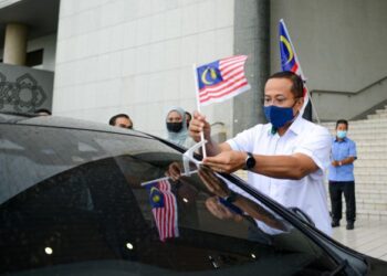 AHMAD Samsuri Mokhtar memasang Jalur Gemilang pada sebuah kenderaan selepas melancarkan Kempen Kibar Jalur Gemilang di Wisma Darul Iman, Kuala Terengganu, hari ini. - FOTO/PUQTRA HAIRRY ROSLI