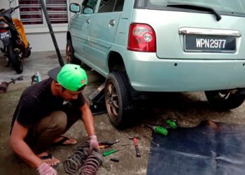 AHMAD Tarmizi Sanusi membaiki kenderaan di kawasan rumah pengguna sepanjang PKP bagi memudahkan orang ramai yang terhad pergerakan di Pontian, Johor. - FOTO/MUHAMMAD ZIKRI