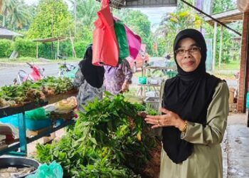 LATIPAH Ahmad bergambar
di hadapan kedai runcit
miliknya.