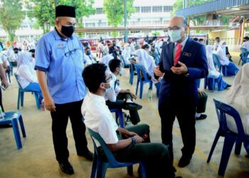 MOHAMMAD Rosli Abdul Rahman (kanan) dan Pengetua Sekolah Menengah Kebangsaan (SMK) Sultan Abu Bakar, Hasrudin Abbas menyantuni calon SPM 2021 di sekolah berkenaan di Kuantan, Pahang. - UTUSAN/SHAIKH AHMAD RAZIF