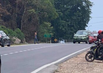 SEORANG lelaki tidak berbaju mengacu parang kepada kenderaan yang lalu di Jalan Temerloh-Maran di Temerloh, Pahang.