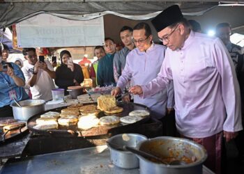 ANWAR Ibrahim (kanan) sambil dibantu Ahmad Samsuri Mokhtar mengoreng martabak ketika melawat Bazar Ramadan Gong Badak, Kuala Nerus, Terengganu, hari ini. - UTUSAN/PUQTRA HAIRRY ROSLI