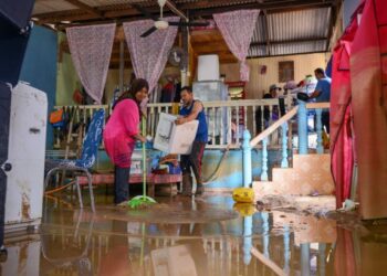 MOHD. Asman Kasman (dua dari kiri) dan isterinya, Dalizah Abdullah dibantu saudara mereka membersihkan rumah mereka yang dinaiki air di Kampung Teladas, Air Putih, Kemaman, Terengganu, semalam. - UTUSAN/PUQTRA HAIRRY ROSLI