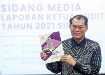 NIK Azman Nik Abdul Majid menunjukkan buku Laporan Ketua Audit Negara 2021 Siri 2 di Kompleks F, Putrajaya. - UTUSAN/FAISOL MUSTAFA